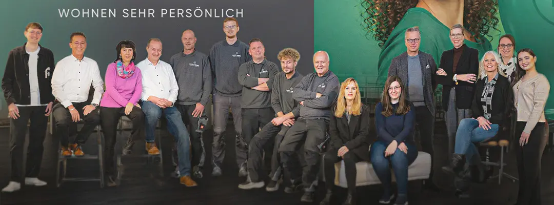 Gruppe von Personen steht und sitzt vor Wand mit Schriftzug Möbel Hensel und Wohnen sehr persönlich sowie großem Portrait rechts